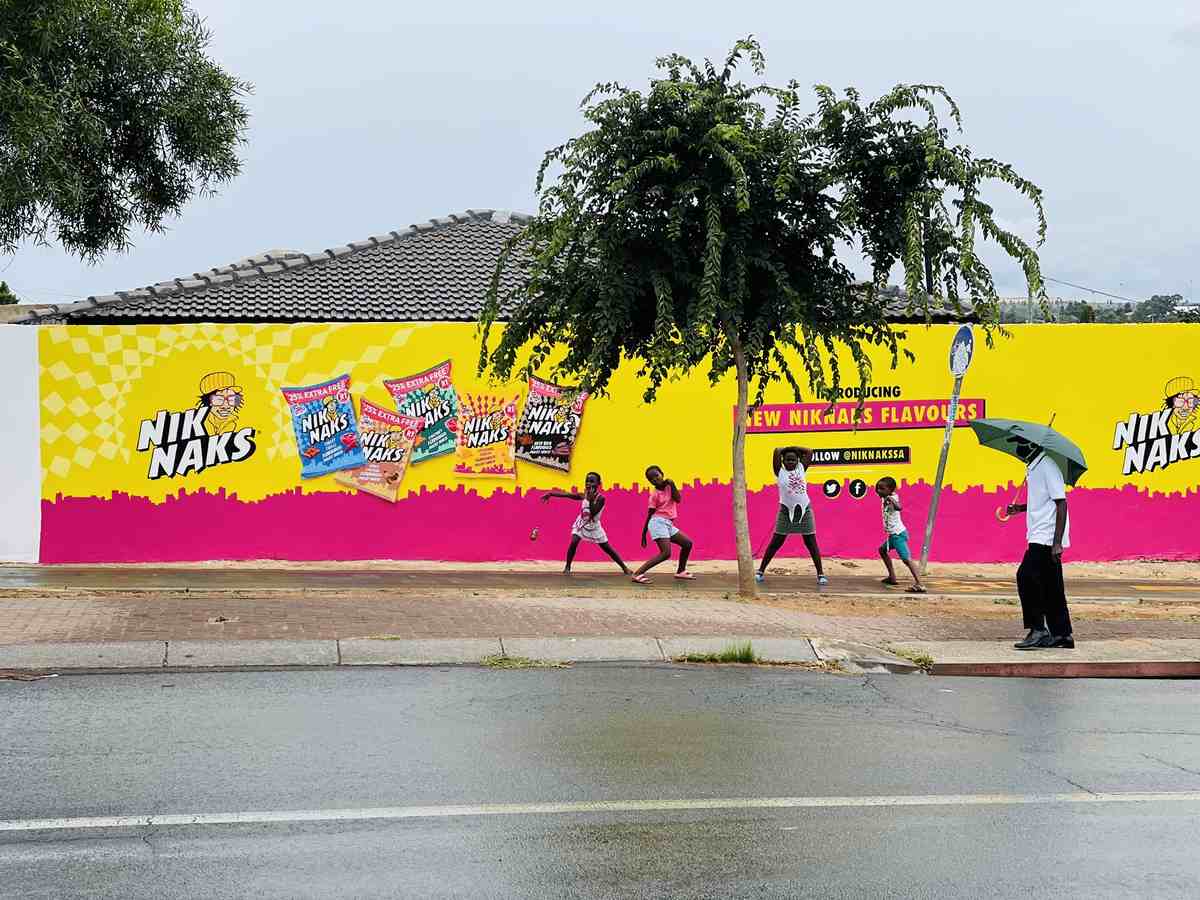 Children playing in front of a freshly painted NikNaks wall mural on a township street